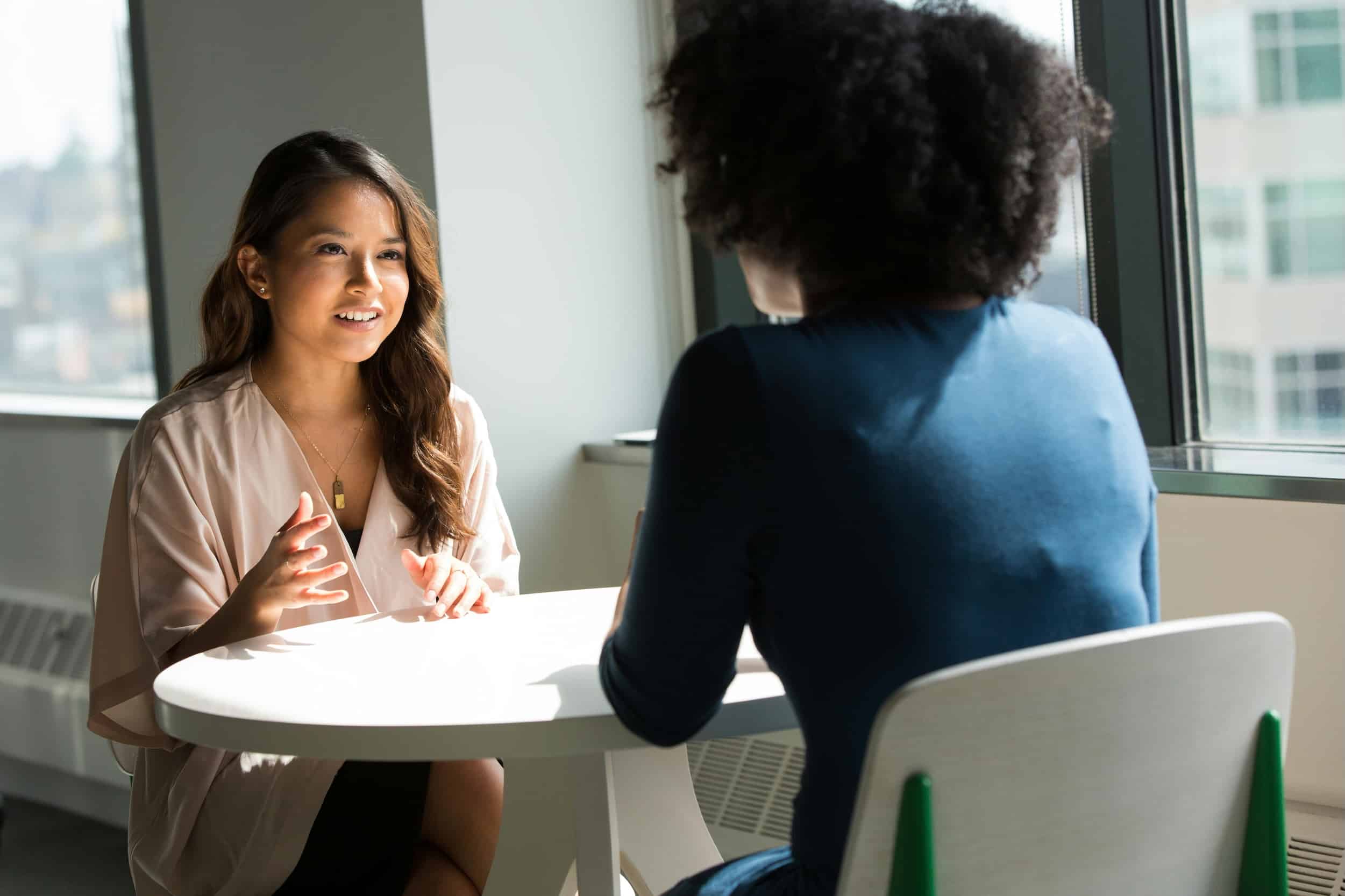 Two professionals having a clear, open conversation at a table, representing straightforward guidance and honest communication.