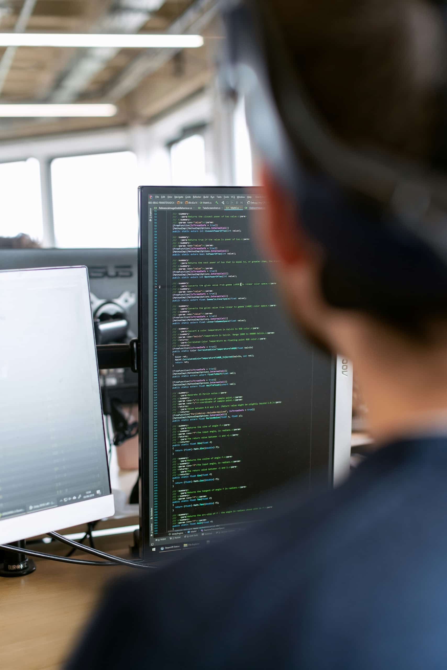 Software developer reviewing code on screen in a tech workspace, representing HR consultancy, organisational design and compensation support for technology companies.